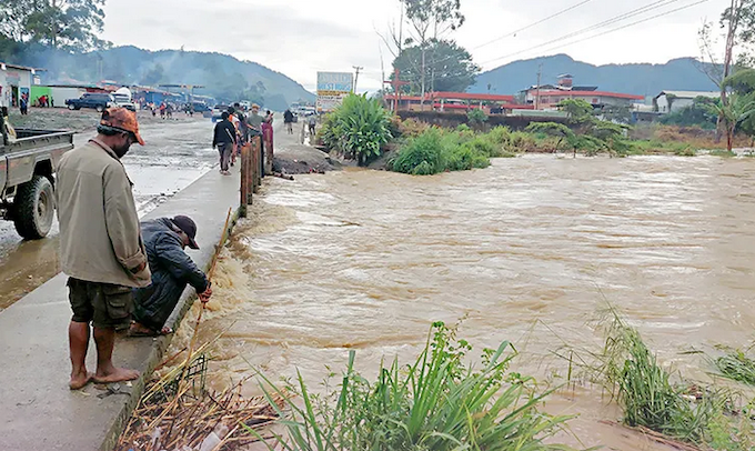 A man tries to clear the debris blocked under the Waghi bridge