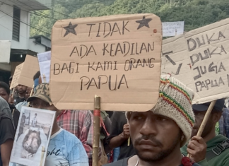 West Papuan demonstrators carry posters depicting torture