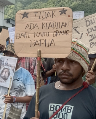West Papuan demonstrators carry posters depicting torture