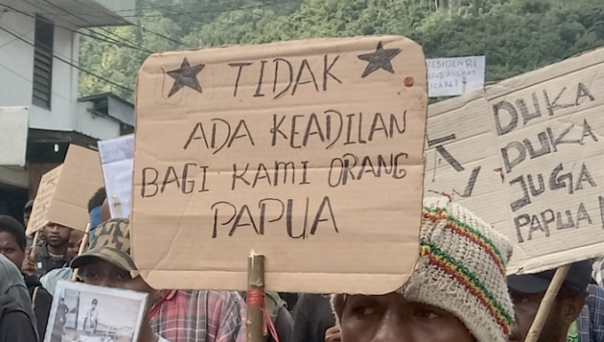 West Papuan demonstrators carry posters depicting torture