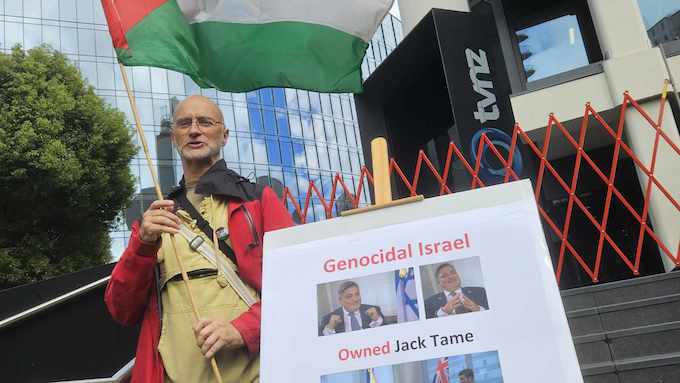 Protester Joseph with a Palestine flag outside the entrance to TVNZ's headquarters today