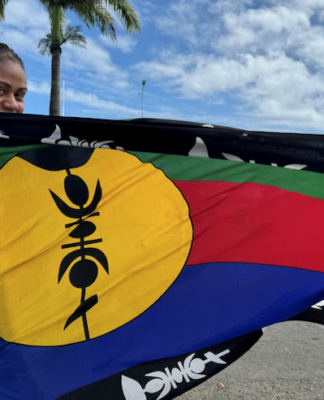 A woman wrapped in Kanak flag of independence with pride
