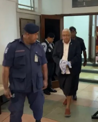 Former Fiji prime minister Voreqe Bainimarama walks out of the Suva High Court escorted by police officers to the be taken to jail today.