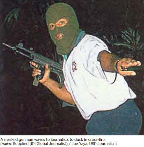 A masked gunman waves to journalists to duck during crossfire