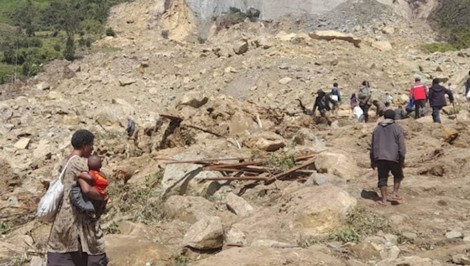 People dig through mud and rocks today after a major landslide at Yambali