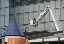 NZ police and firefighters work to get the pro-Palestinian protester with flag down from the roof of Christchurch City Council
