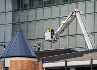 NZ police and firefighters work to get the pro-Palestinian protester with flag down from the roof of Christchurch City Council