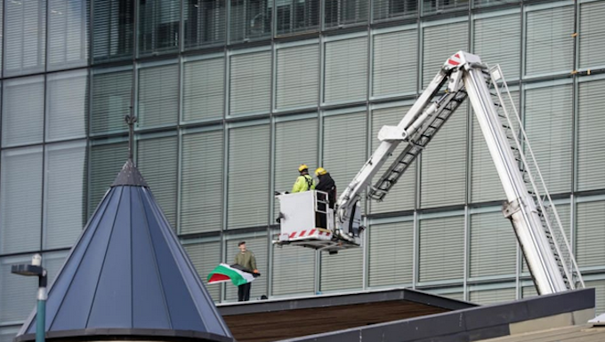 NZ police and firefighters work to get the pro-Palestinian protester with flag down from the roof of Christchurch City Council