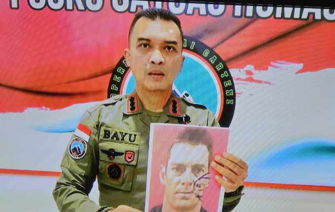 Commander Bayu Suseno holds a photo of the NZ pilot Glen Conning