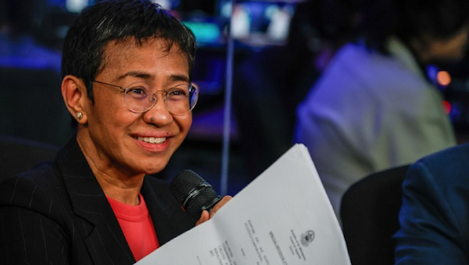 Standing in front of her news organisation’s logo, Rappler chief executive Maria Ressa