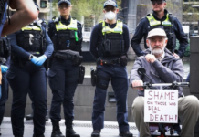 A protester with a "Shame on those who deal in death!" placard