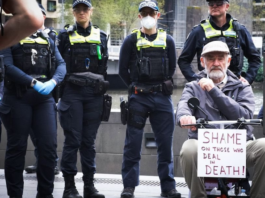 A protester with a "Shame on those who deal in death!" placard