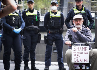 A protester with a "Shame on those who deal in death!" placard