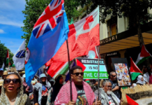 Pacific flags -- Fiji and Tonga -- and protesters in support of Palestine at a rally in New Zealand's largest city Auckland