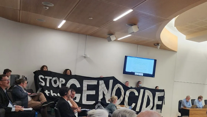 Christchurch citizens hold up a "Stop the genocide" banner before yesterday's council vote
