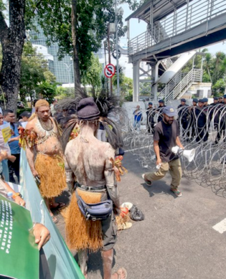 Security forces watch from behind barbed wire as indigenous Papuans from Merauke in the Indonesia-ruled Melanesian region protest