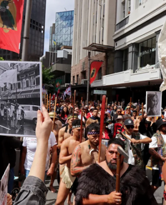 John Miller's photograph of the 1975 Land March held up in the same location at the 2024 Hīkoi mō te Tiriti in Pōneke Wellington.