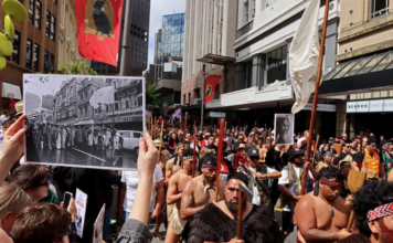 John Miller's photograph of the 1975 Land March held up in the same location at the 2024 Hīkoi mō te Tiriti in Pōneke Wellington.