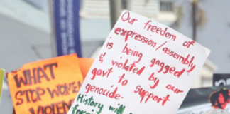 An "Our freedom of expression/assembly is being gagged and violated by our government to support genocide" placard