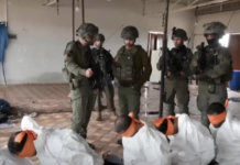 This screenshot from a video broadcast on Israeli channel Now 14 shows an officer and four soldiers of Israel’s Givati Brigade standing next to Palestinian detainees