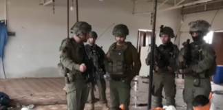 This screenshot from a video broadcast on Israeli channel Now 14 shows an officer and four soldiers of Israel’s Givati Brigade standing next to Palestinian detainees