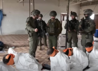 This screenshot from a video broadcast on Israeli channel Now 14 shows an officer and four soldiers of Israel’s Givati Brigade standing next to Palestinian detainees