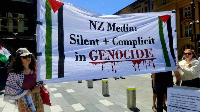 A banner condemning New Zealand media for being "silent and complicit"