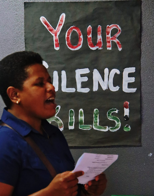 A Fiji protester with a "Your silence kills" placard