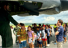 A group of schoolchildren boarding a military aircraft