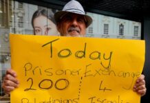 A protester for Palestine holds up a poster in Te Komititanga Square