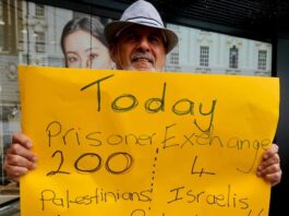 A protester for Palestine holds up a poster in Te Komititanga Square