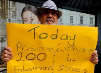 A protester for Palestine holds up a poster in Te Komititanga Square