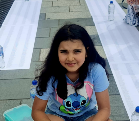 A young girl keeps vigil besides lists of thousands of names of the more than 47,000 Palestinians killed by Israel in the war on Gaza