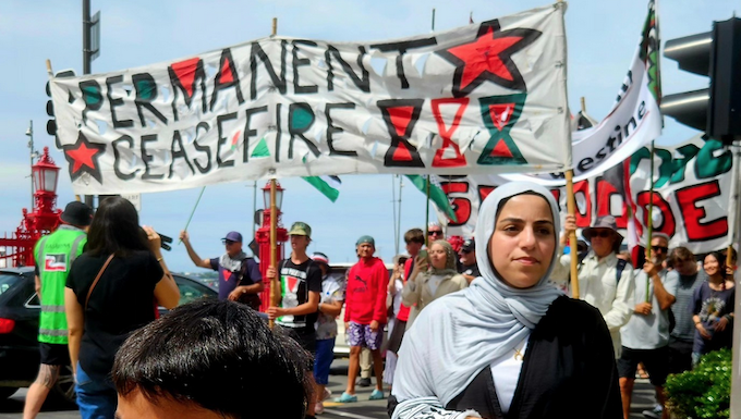 Cheerleader Ali Gouda leads the Palestine genocide protesters into Te Komititanga Square during the "march of the martyrs"