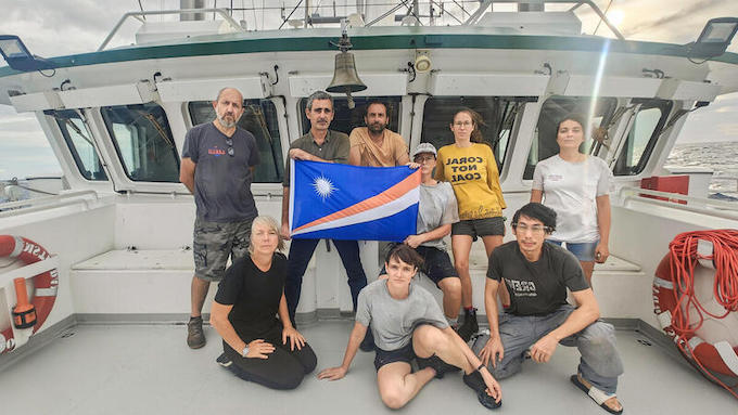 The Rainbow Warrior crew members hold the Marshall Islands flag 