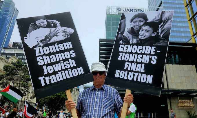 New Zealand cartoonist Malcolm Evans with two of his anti-Zionism 