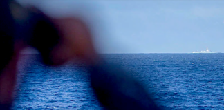 A crew member on board the RAN frigate HMAS Stuart monitors the Chinese Navy's missile destroyer Zunyi and the supply ship Weishanhu