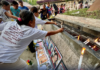 Families and survivors hold a symbolic offering of flowers and lighting of candles