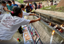 Families and survivors hold a symbolic offering of flowers and lighting of candles