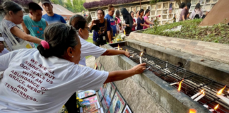 Families and survivors hold a symbolic offering of flowers and lighting of candles