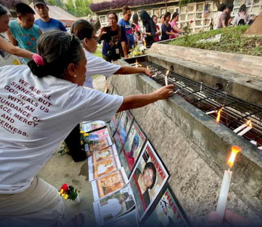 Families and survivors hold a symbolic offering of flowers and lighting of candles