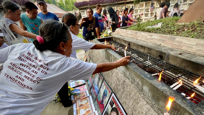 Families and survivors hold a symbolic offering of flowers and lighting of candles