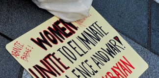 A Filipino "Women unite to eliminate violence and war" placard