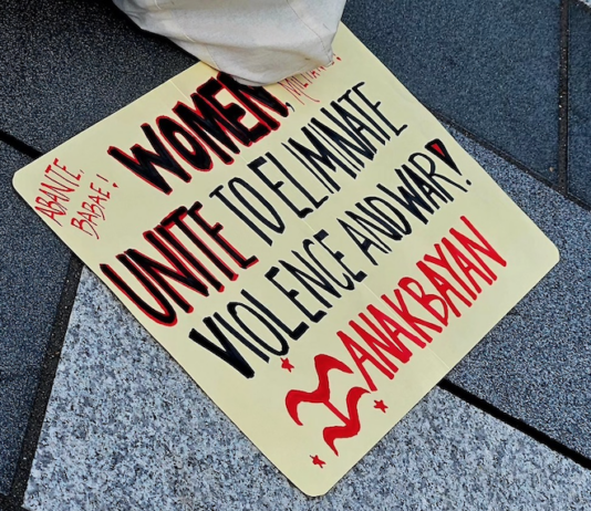 A Filipino "Women unite to eliminate violence and war" placard