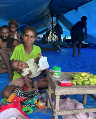 An evicted mother and baby selling betelnut in their temporary tent village on the outskirts of the capital, Port Moresby
