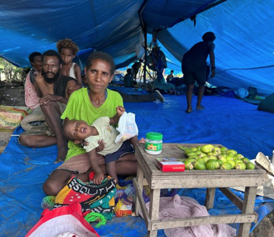 An evicted mother and baby selling betelnut in their temporary tent village on the outskirts of the capital, Port Moresby