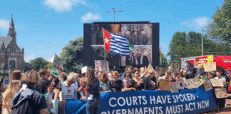 A West Papuan Morning Star flag of independence flies higm among dozens of climate activists - from both the Netherlands and abroad - gathered on a square outside the court