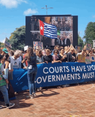 A West Papuan Morning Star flag of independence flies higm among dozens of climate activists - from both the Netherlands and abroad - gathered on a square outside the court