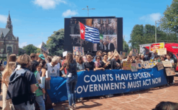 A West Papuan Morning Star flag of independence flies higm among dozens of climate activists - from both the Netherlands and abroad - gathered on a square outside the court