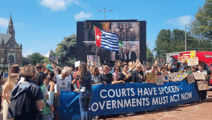 A West Papuan Morning Star flag of independence flies higm among dozens of climate activists - from both the Netherlands and abroad - gathered on a square outside the court